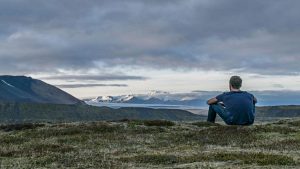 A person sitting on a mountain edge looking at the view without a phone, representing the Deadzoning trend.
