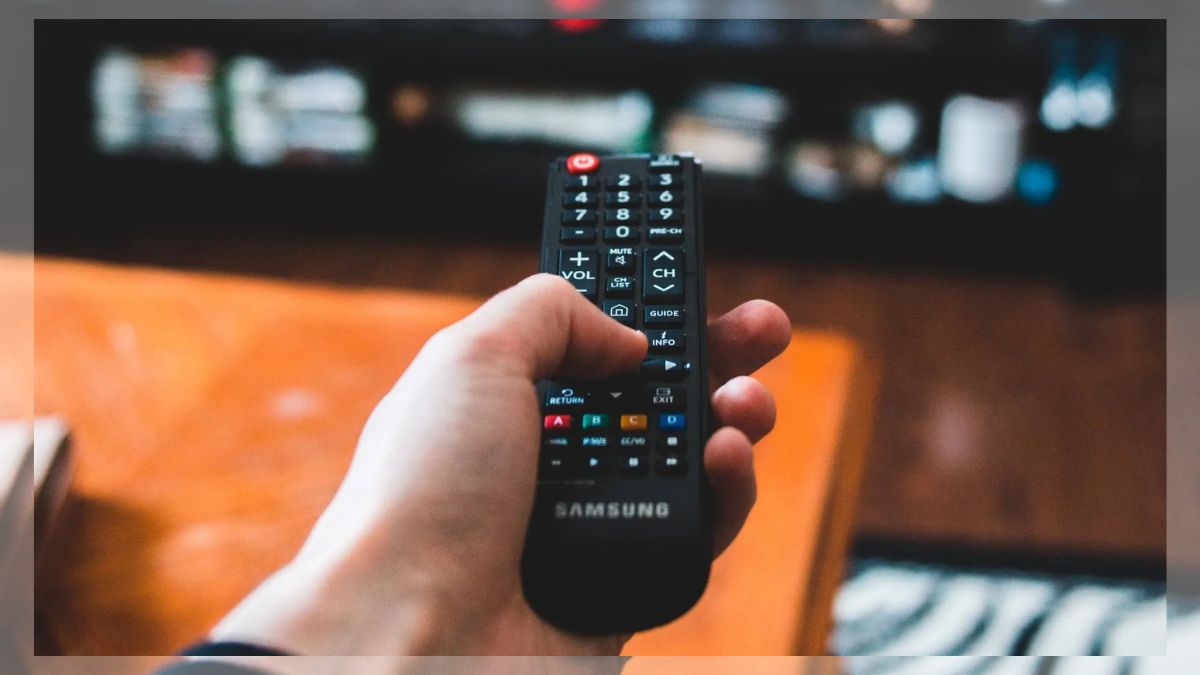 A person hitting a television remote control to make it work due to battery contact oxidation.