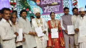 ஆடம்பர பரிசுகளை ஒதுக்கிவிட்டு ஒட்டுமொத்த ஊர் மக்கள் 3,500 பேருக்கும் தலா ரூ.1 லட்சத்திற்கு விபத்து காப்பீடு எடுத்துக்கொடுத்த தந்தை! Groom Siddheshwar Pethkar and his bride standing on the wedding stage holding official group insurance policy documents for villagers.