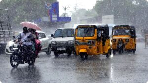 Dark monsoon rain clouds hovering over a rural green landscape in Tamil Nadu with active rainfall layers falling on roads.