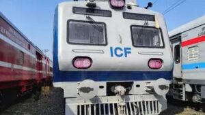 Modern silver and red accented air-conditioned local suburban train standing at a busy Chennai railway station platform with daily commuters.