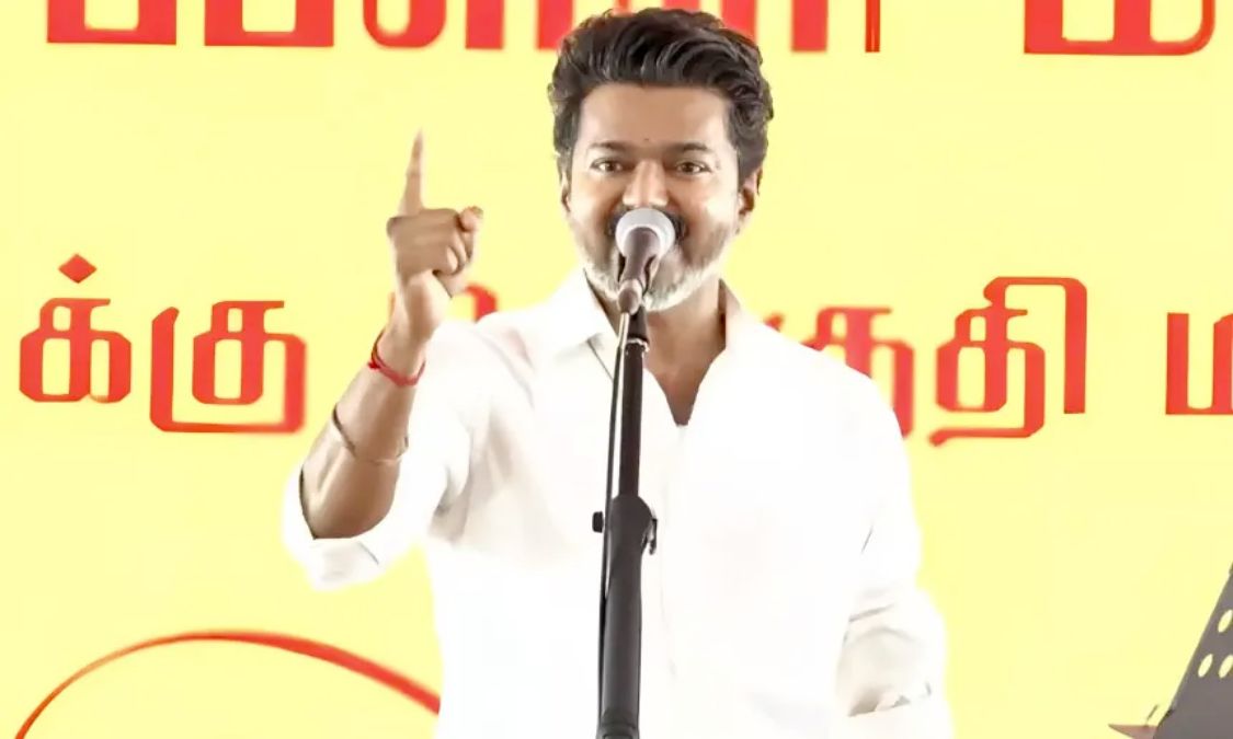 Tamil Nadu Chief Minister Joseph Vijay speaking passionately into a microphone at a massive political rally background stage setup.