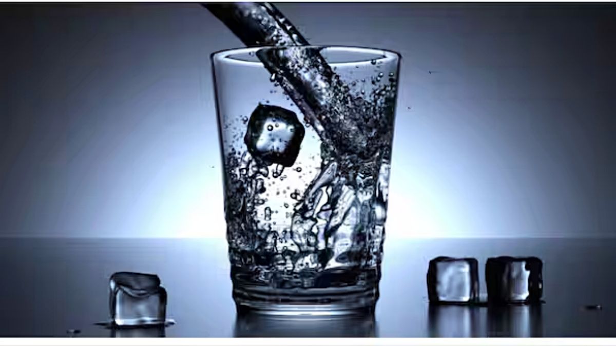 A person holding a sweating glass of ice-cold water after stepping inside a home from bright summer sunlight outside.