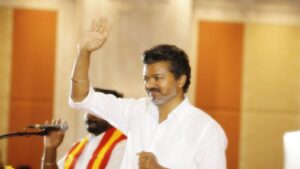 விஜய் அடுத்த அதிரடி! தமிழக வெற்றி கழகத்திற்குப் புதிய செய்தி சேனல்? அரசியல் மற்றும் ஊடக வட்டாரங்களில் பலத்த விவாதம்! A television broadcasting studio camera set up with abstract digital political flags and screens in the background.